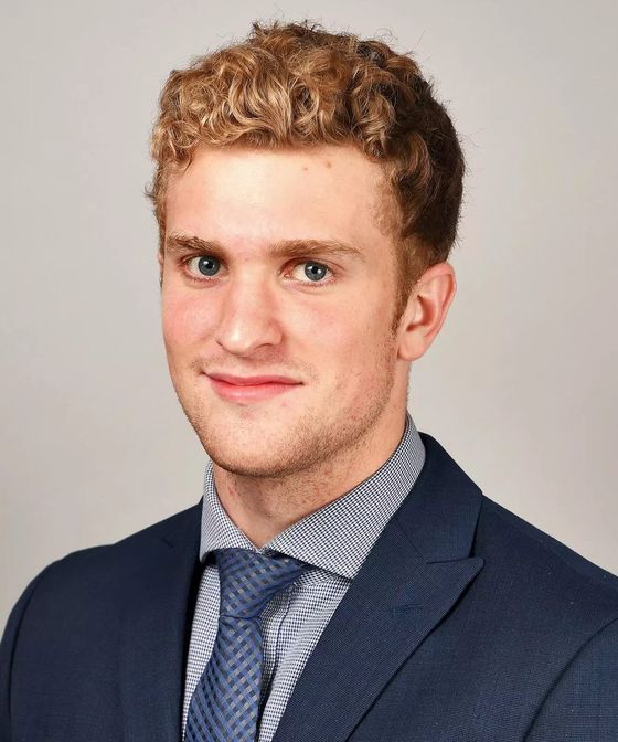 Headshot of Merek Pipes in a navy suit